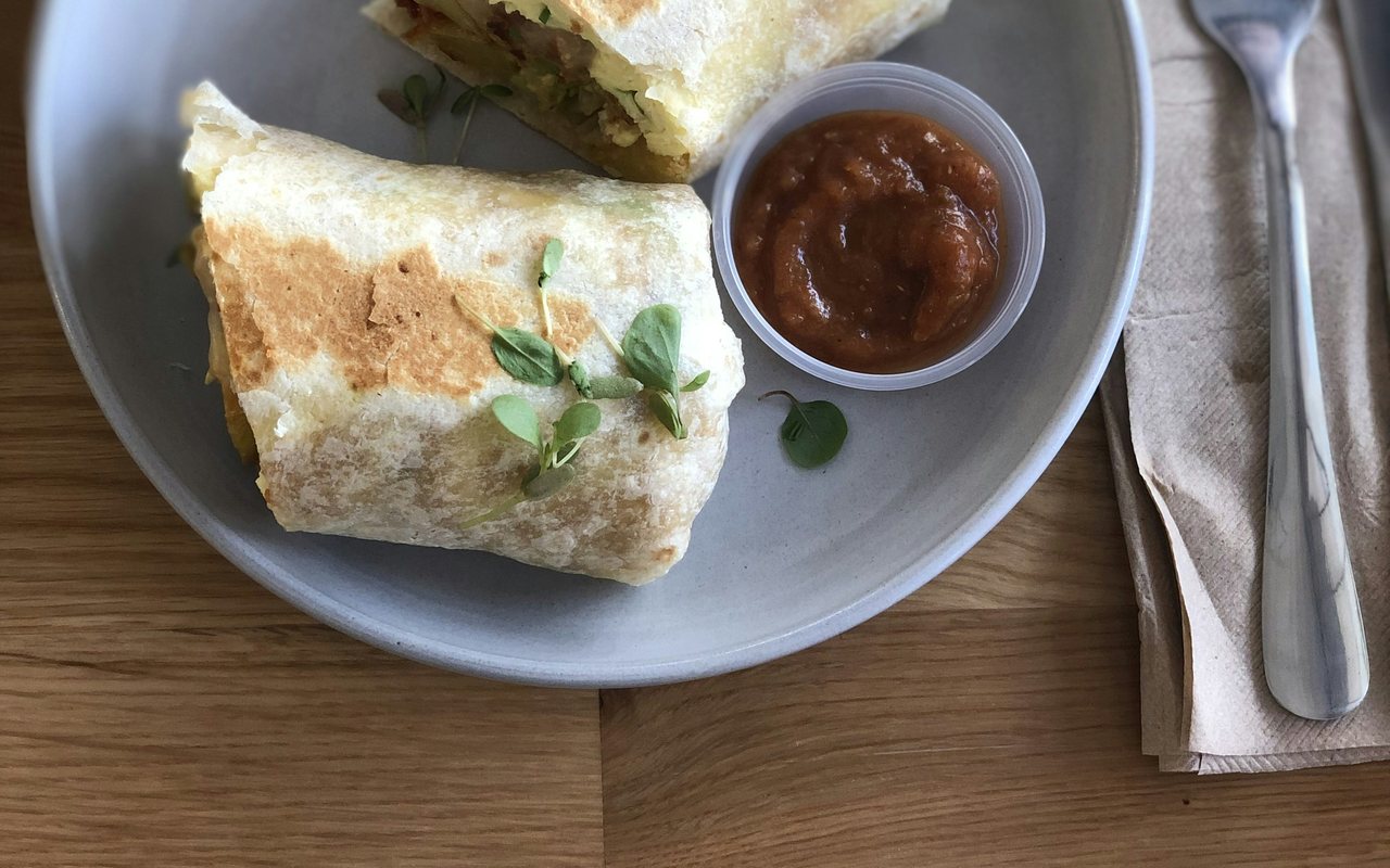 Two toasted breakfast burrito halves served with salsa on a gray plate.