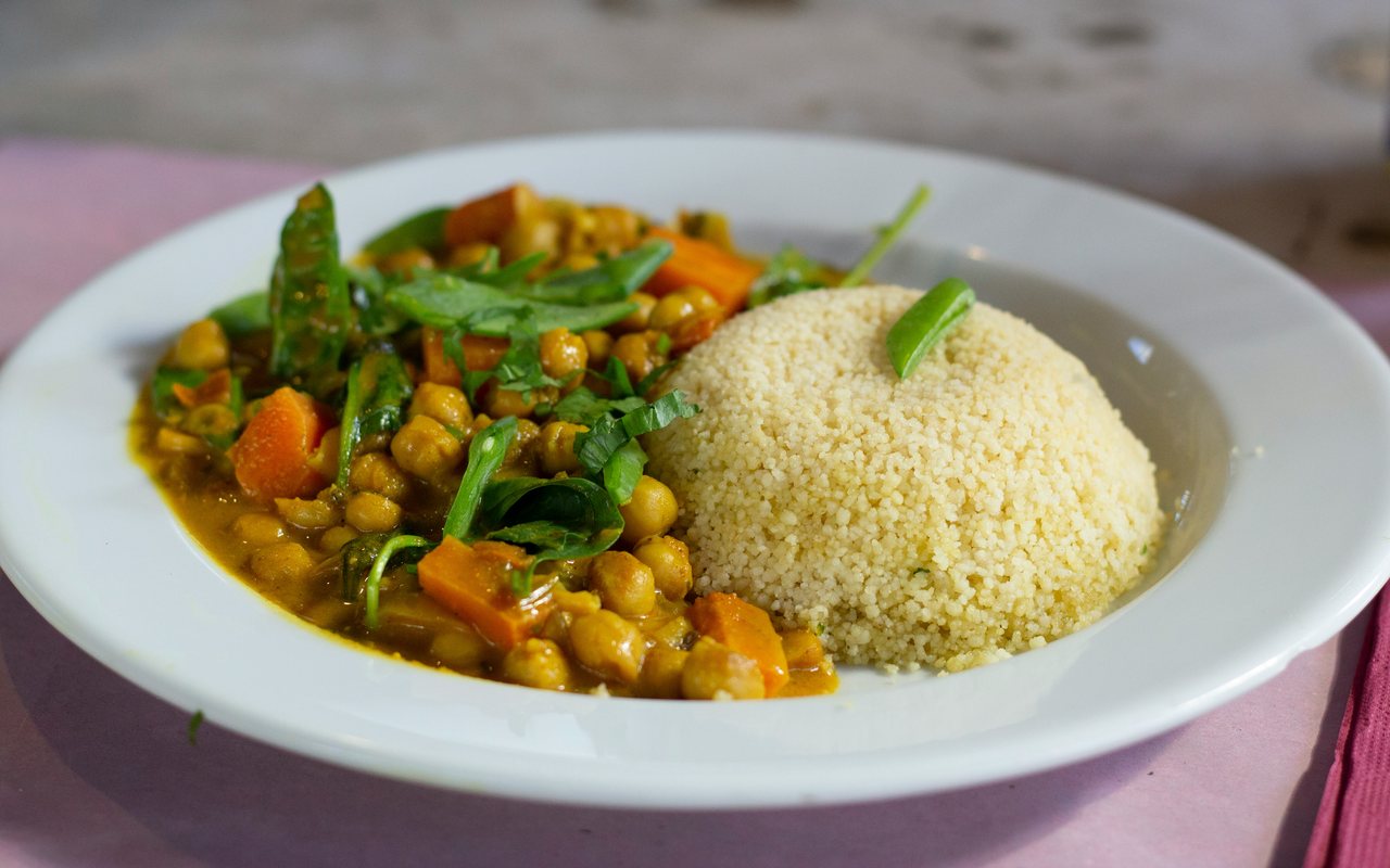Chickpea curry served with couscous and leafy greens.