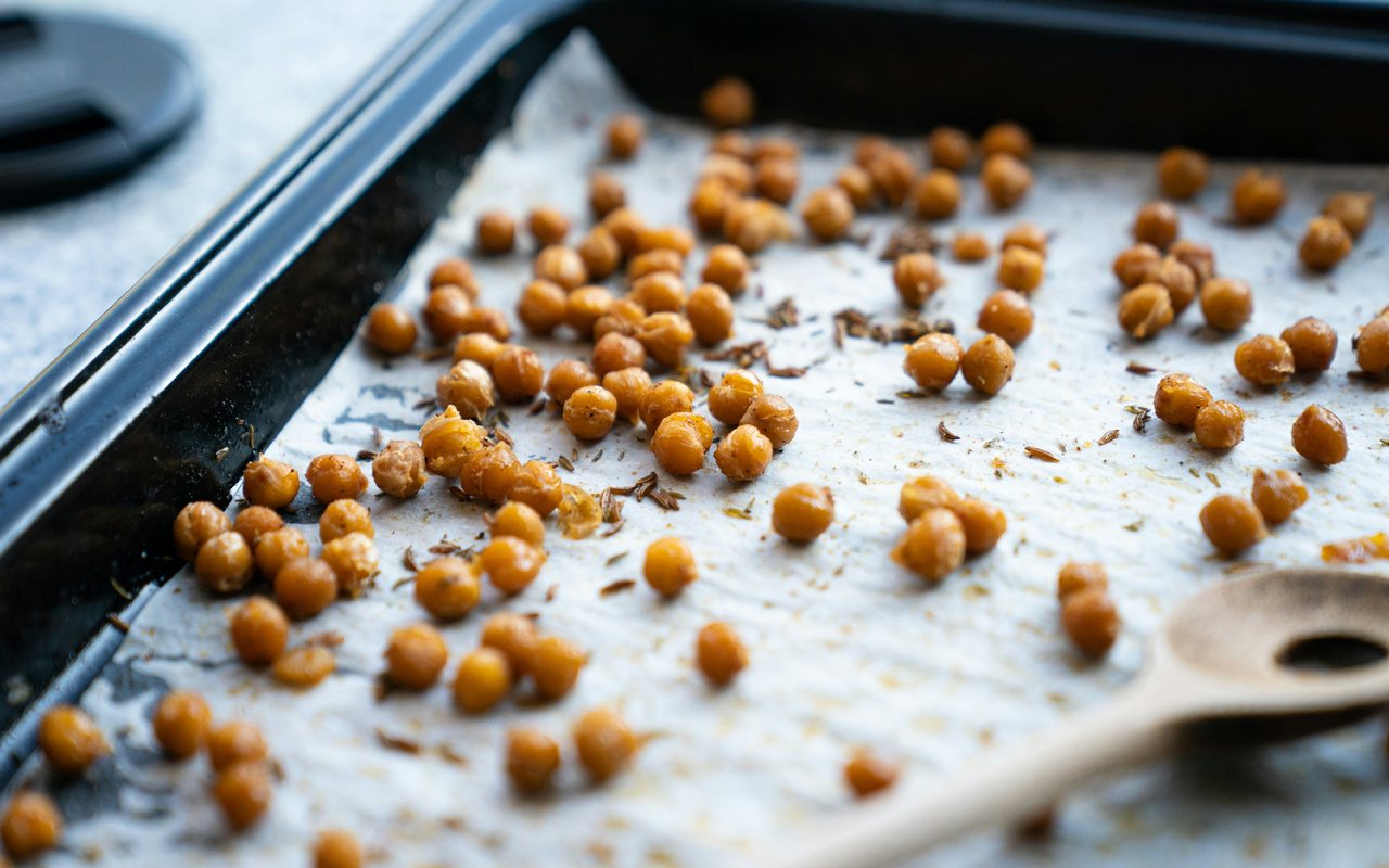 Roasted chickpeas scattered across a parchment-lined baking sheet.