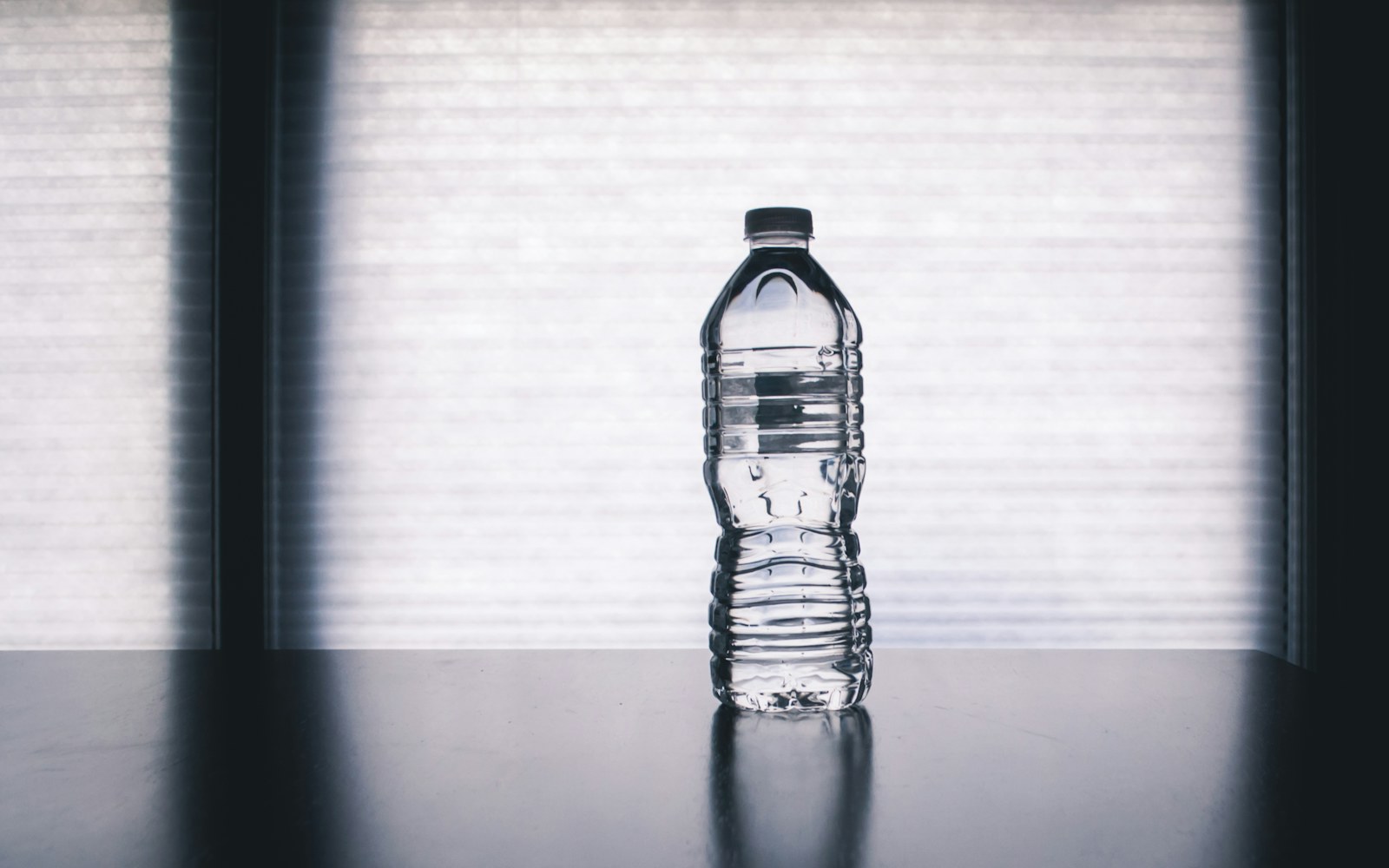 Clear water bottle standing in front of a bright window