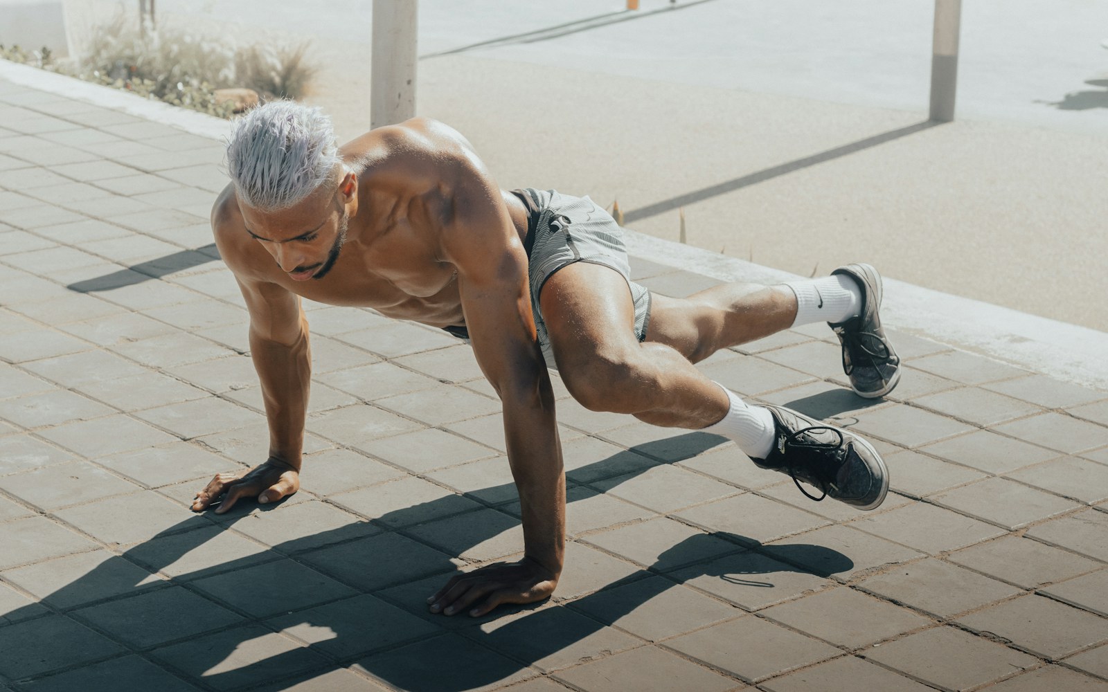 Man performs a bodyweight mountain climber on a paved path