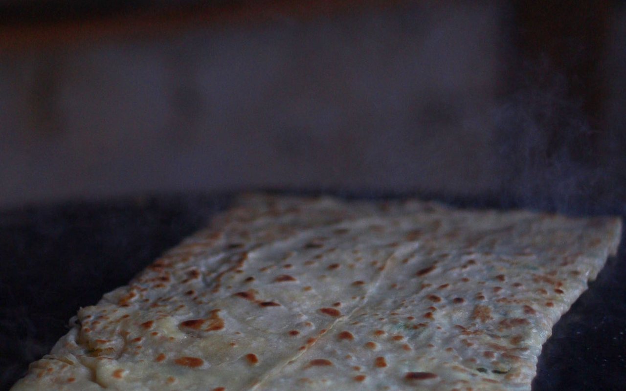 Square folded gözleme flatbreads with browned spots stacked on a plate