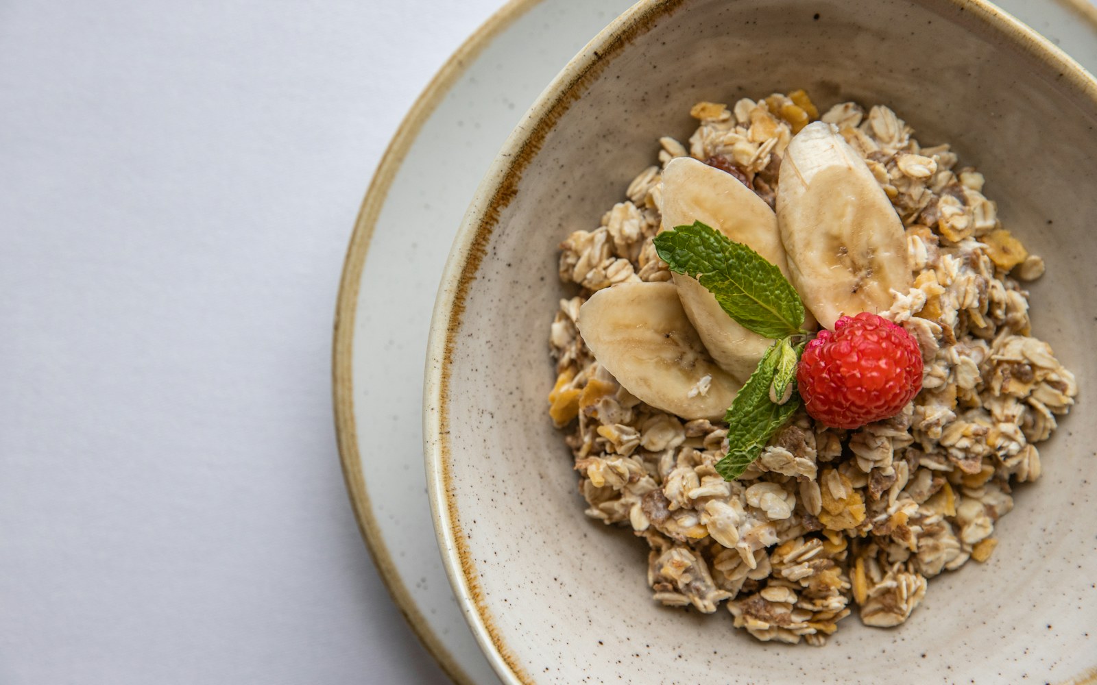 Bowl of oats topped with banana, raspberry, and mint