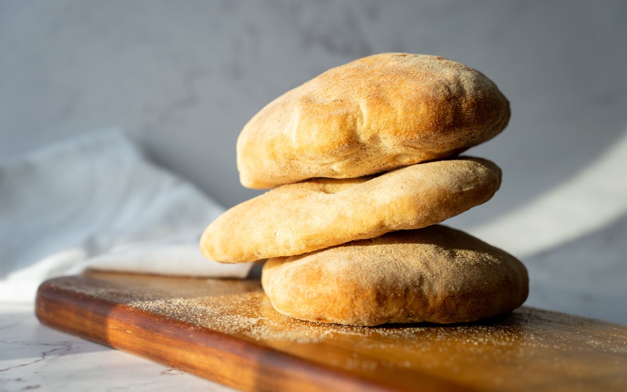 Six round puffed pita breads with lightly browned surfaces