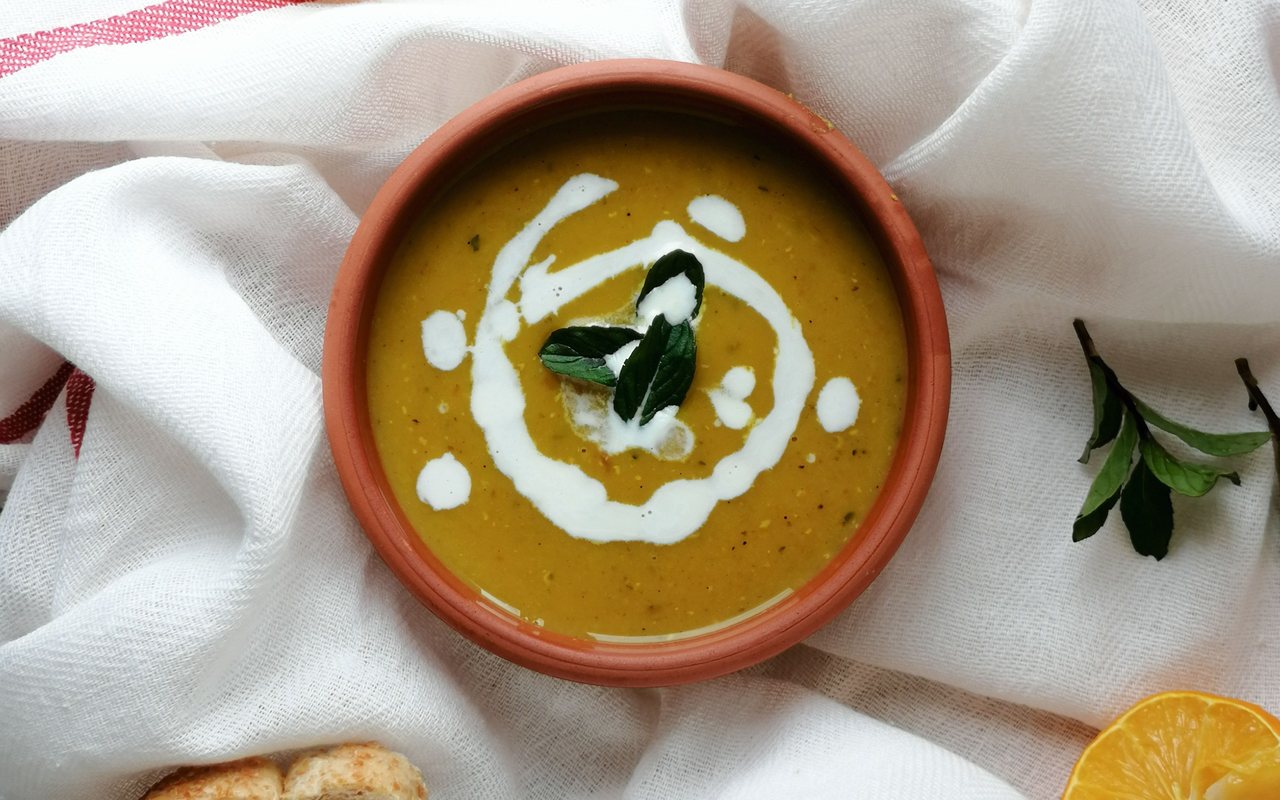 Bowl of smooth golden Turkish lentil soup with red pepper butter