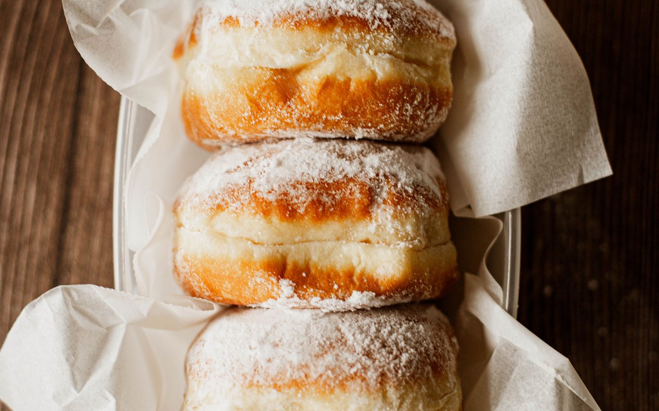Round fried donuts coated in cinnamon sugar and filled with vanilla custard