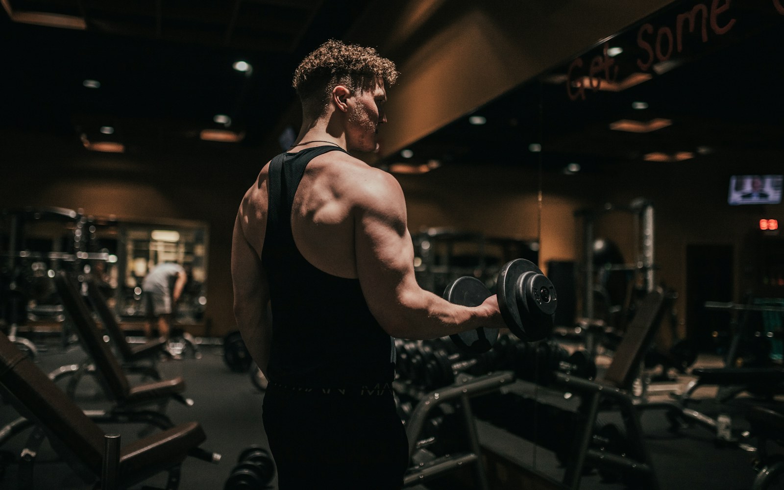 Man performs a dumbbell curl in a gym