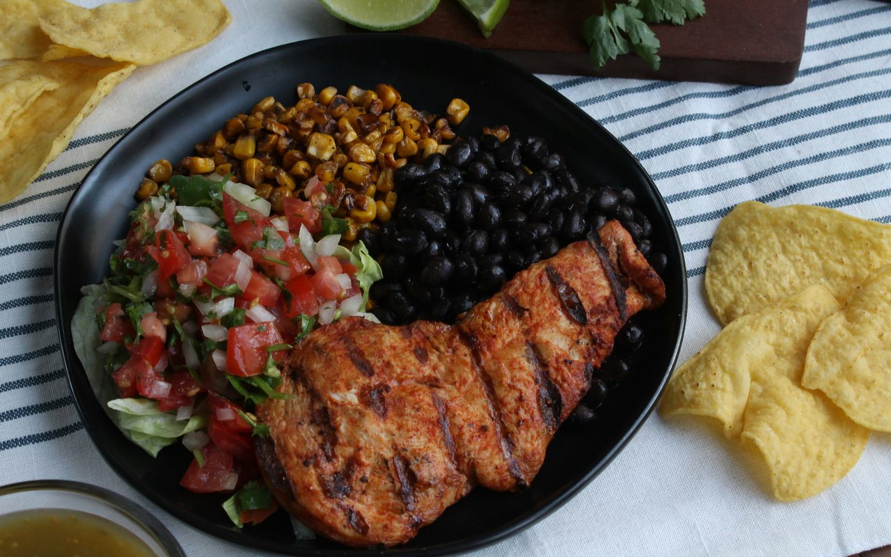 Grilled chicken with charred corn, black beans, fresh tomato salsa, and tortilla chips.