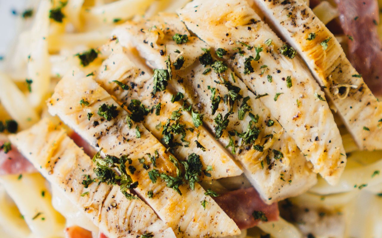 Creamy pasta with chicken strips, mushrooms, Parmesan, and chopped green garlic