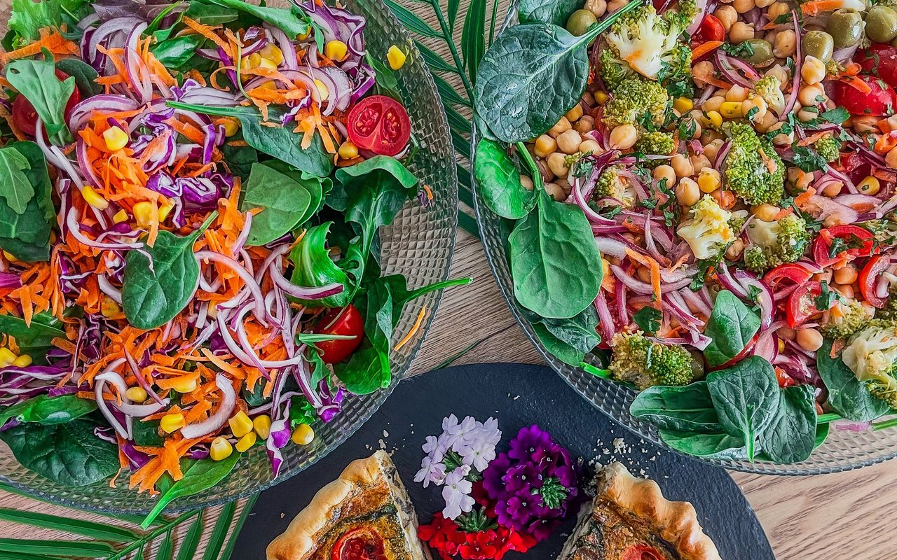 Two colorful salad bowls with broccoli, red cabbage, carrot, and corn