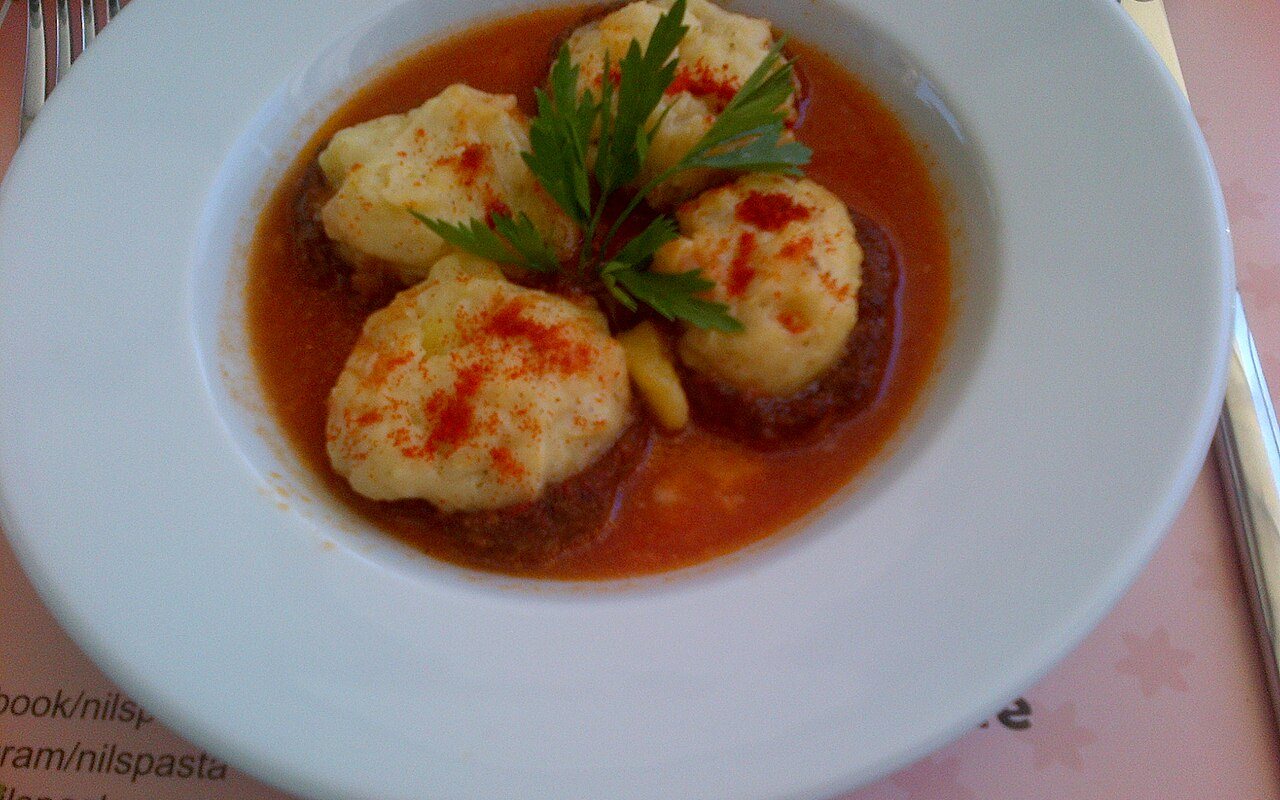 Baked meatball cups filled with mashed potato and melted cheese in tomato sauce