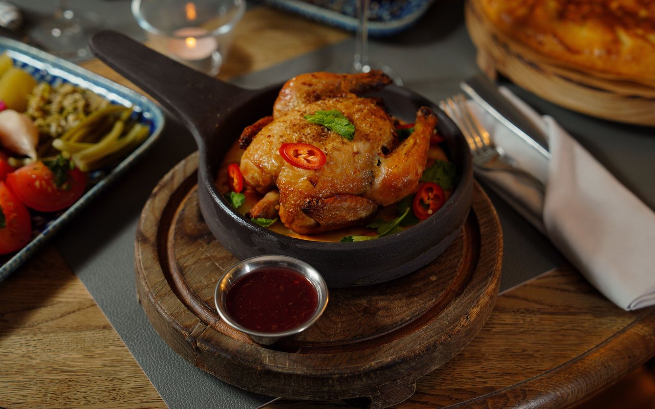 Whole roast chicken with browned skin, potato, onion, and herbs