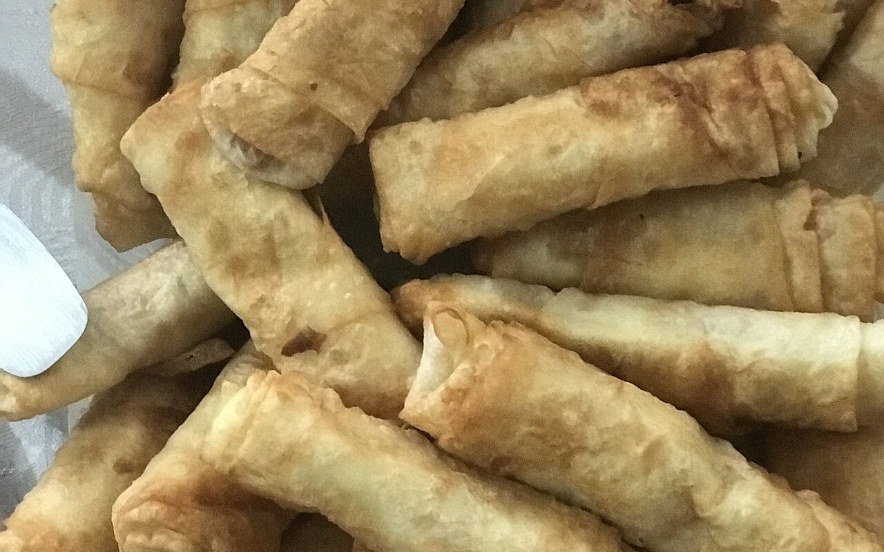Golden crumb-coated rolled pastries filled with meat, cheese, peppers, and tomato