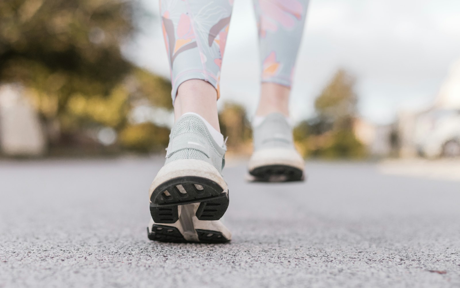 Close-up of a person walking outdoors in pale running shoes