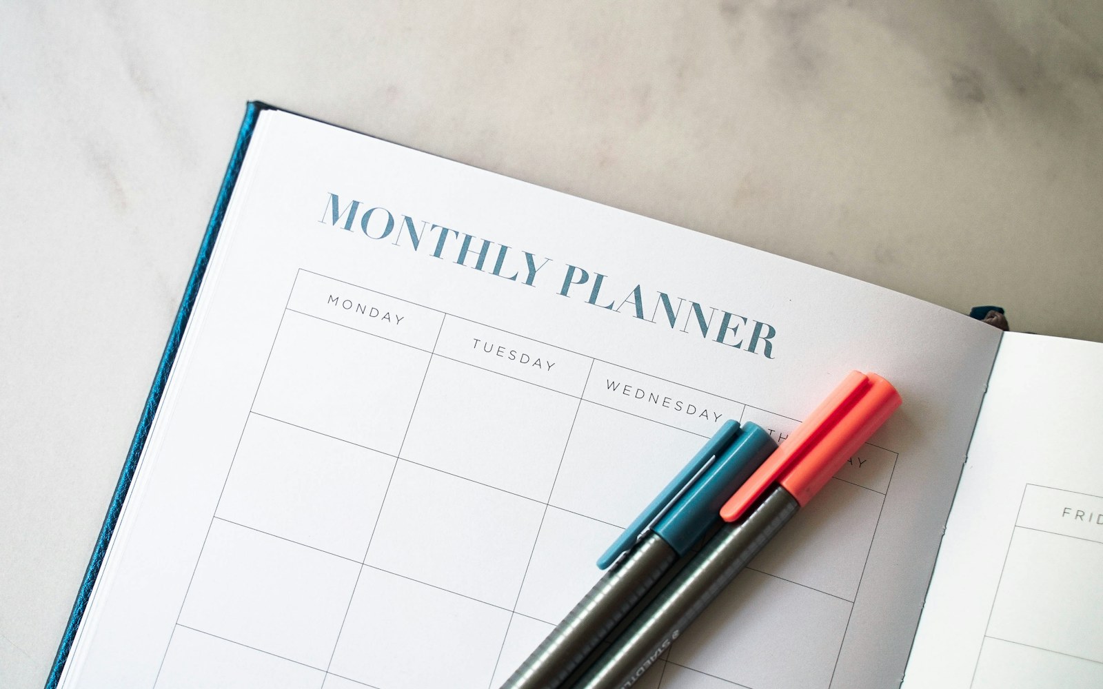 Open monthly planner with two pens