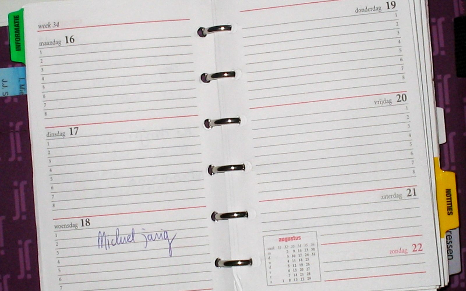 Open ring-bound weekly planner with one handwritten entry.