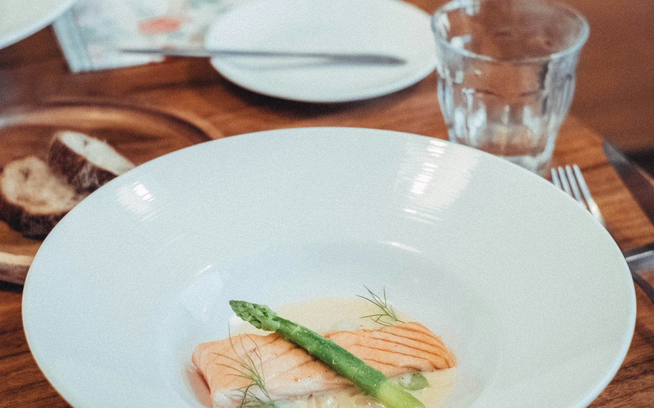 Cooked salmon fillet with asparagus, lemon, and creamy dill sauce.