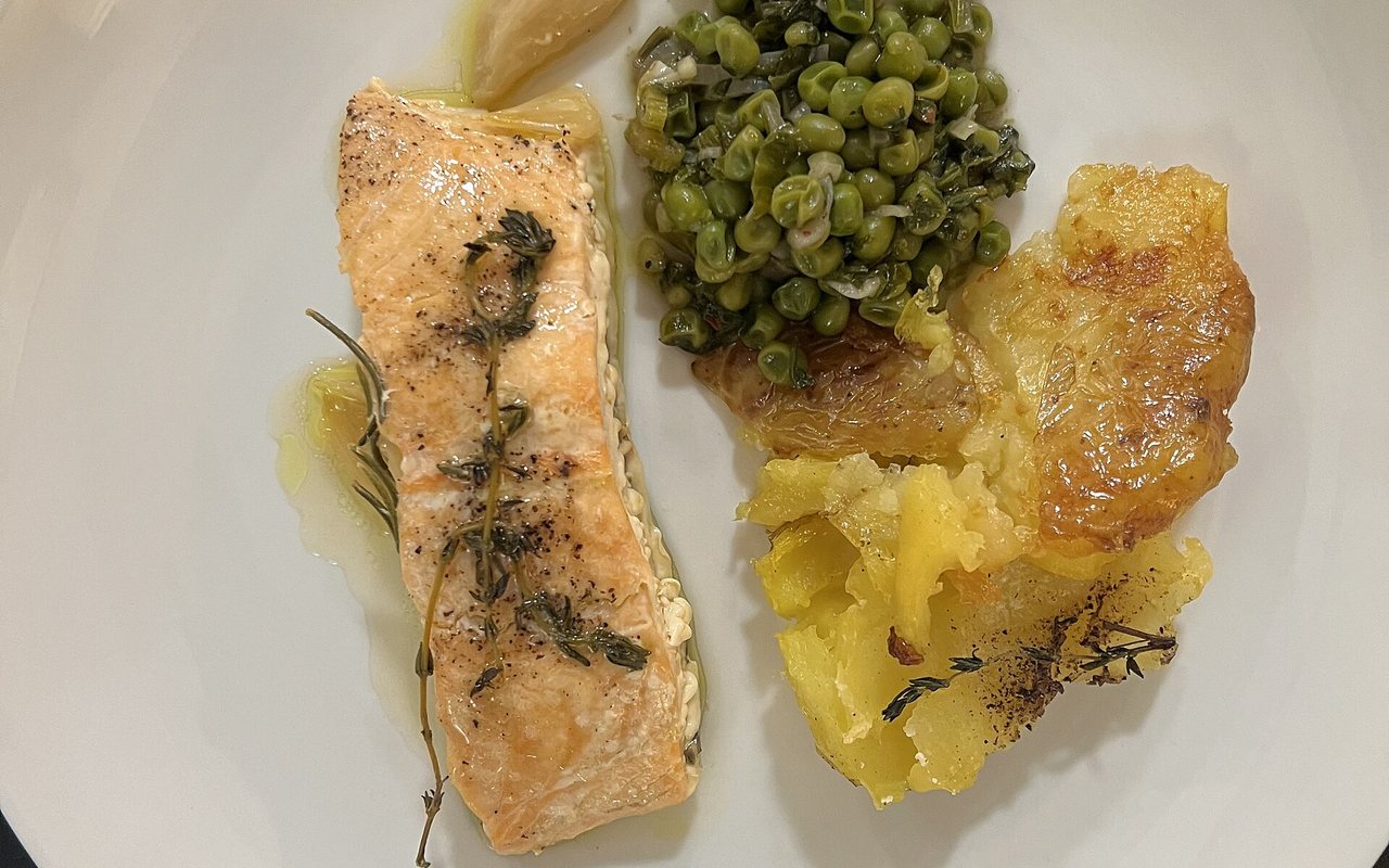 Baked salmon fillets with sliced potatoes, onion, lemon, and herbs on a sheet pan
