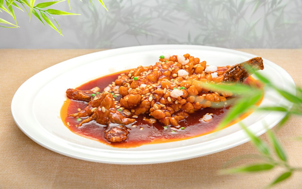 Soy-glazed chicken pieces with peanuts and sliced scallions