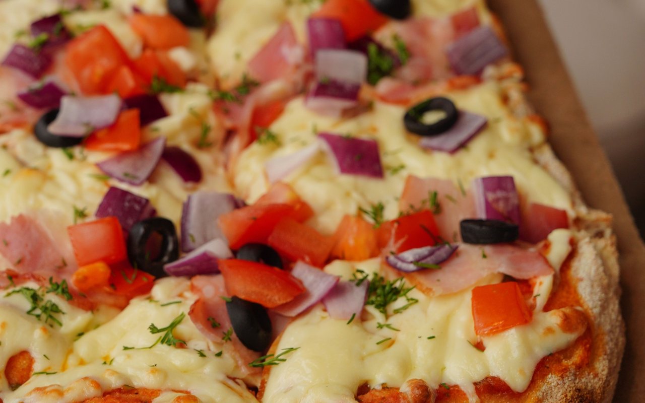 Large rectangular homemade pizza topped with sucuk, mushrooms, peppers, and cheese