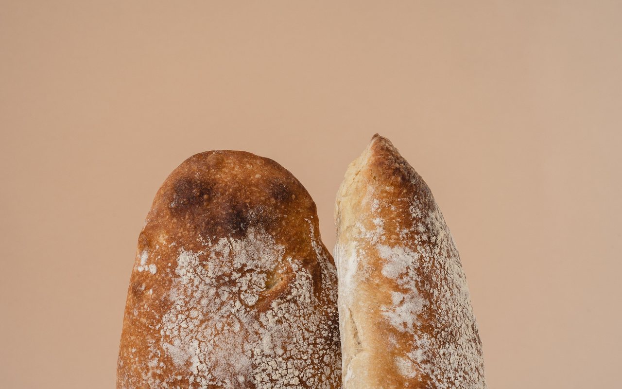 Two flour-dusted ciabatta rolls against a warm beige background