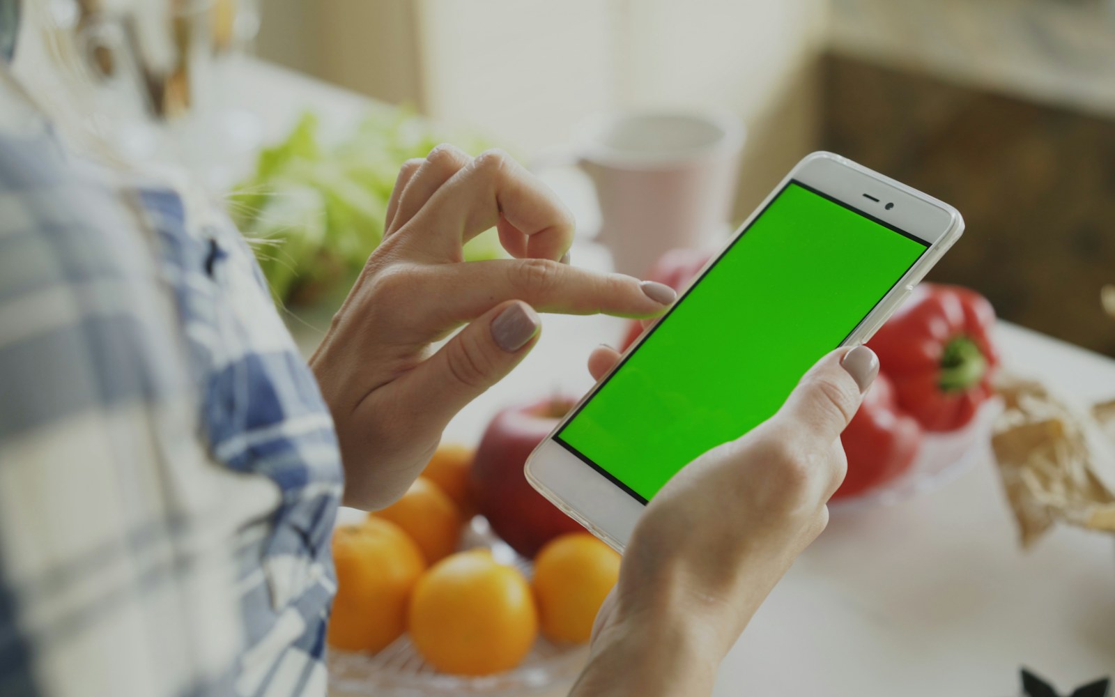 Person holds a blank-screen smartphone beside fresh produce