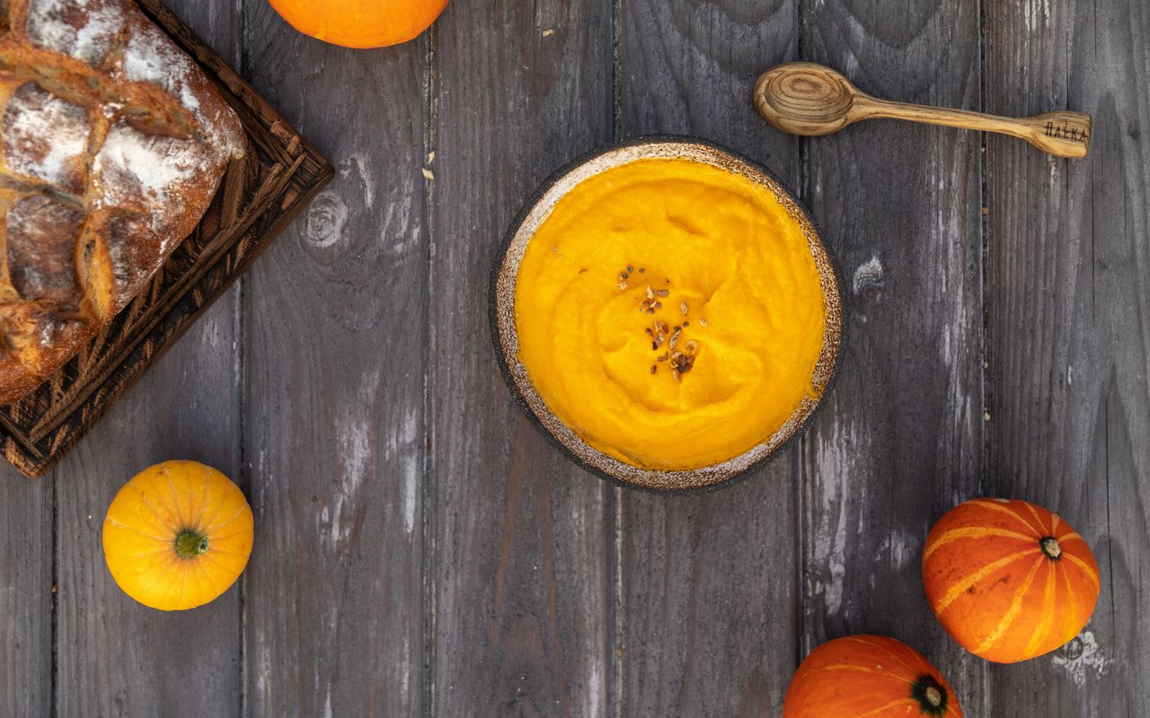 Smooth orange pumpkin soup topped with grated Parmesan and fresh dill
