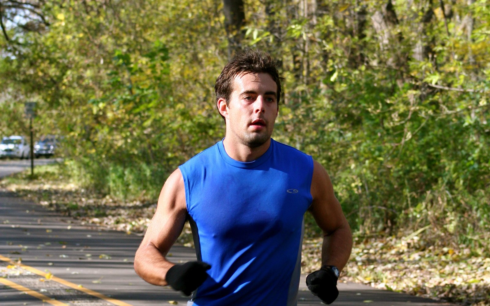 Sweaty man running on a tree-lined path.
