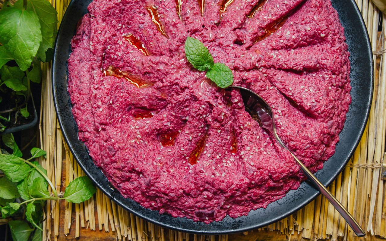 Bright pink beet hummus in a shallow serving bowl