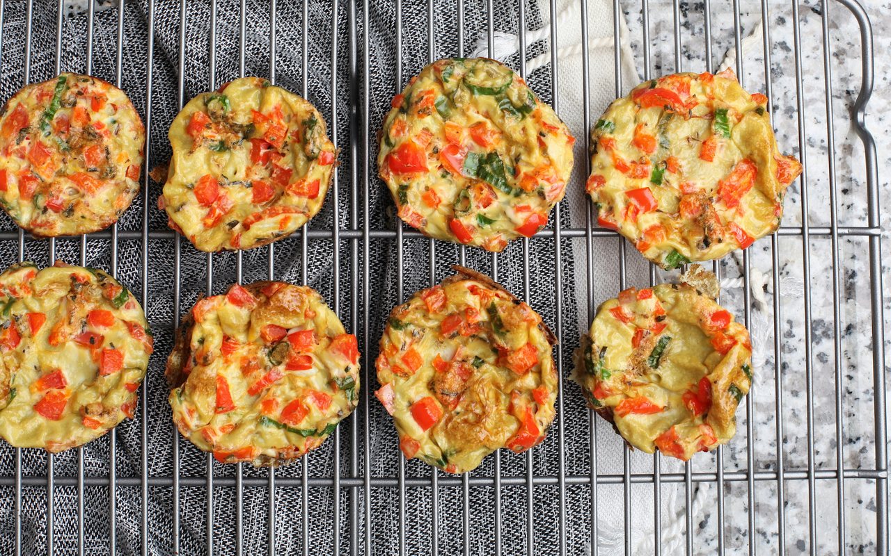 Eight spinach and red pepper egg bites cooling on a wire rack.