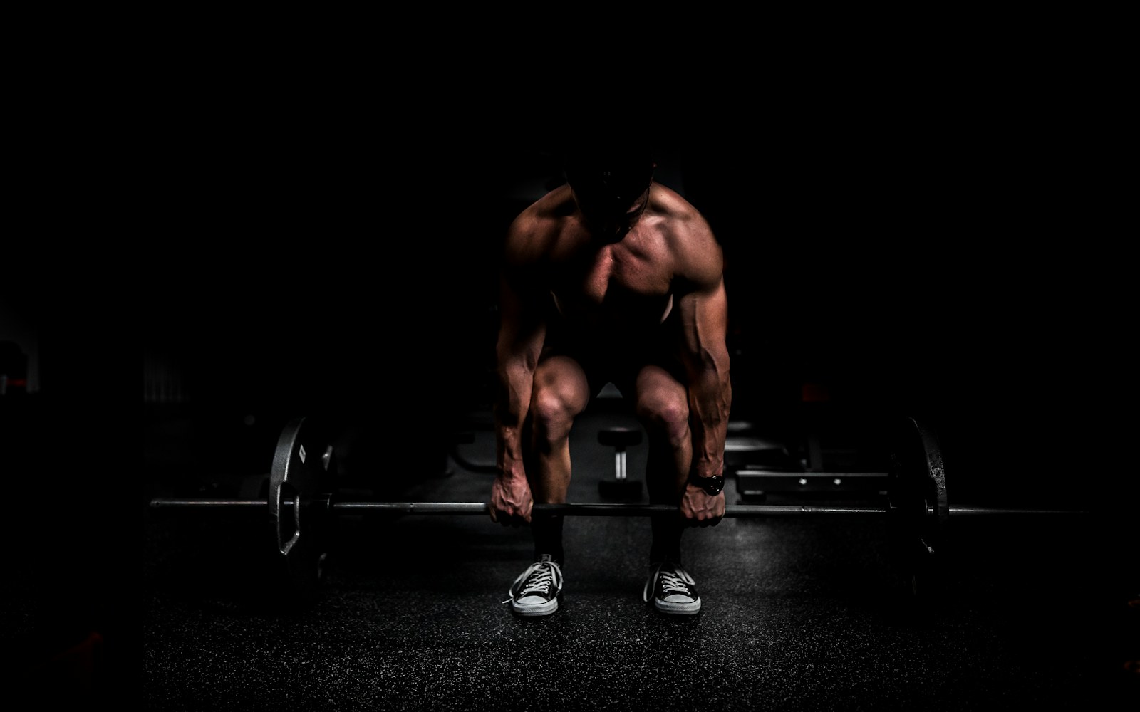 Athlete prepares to deadlift in a dark gym