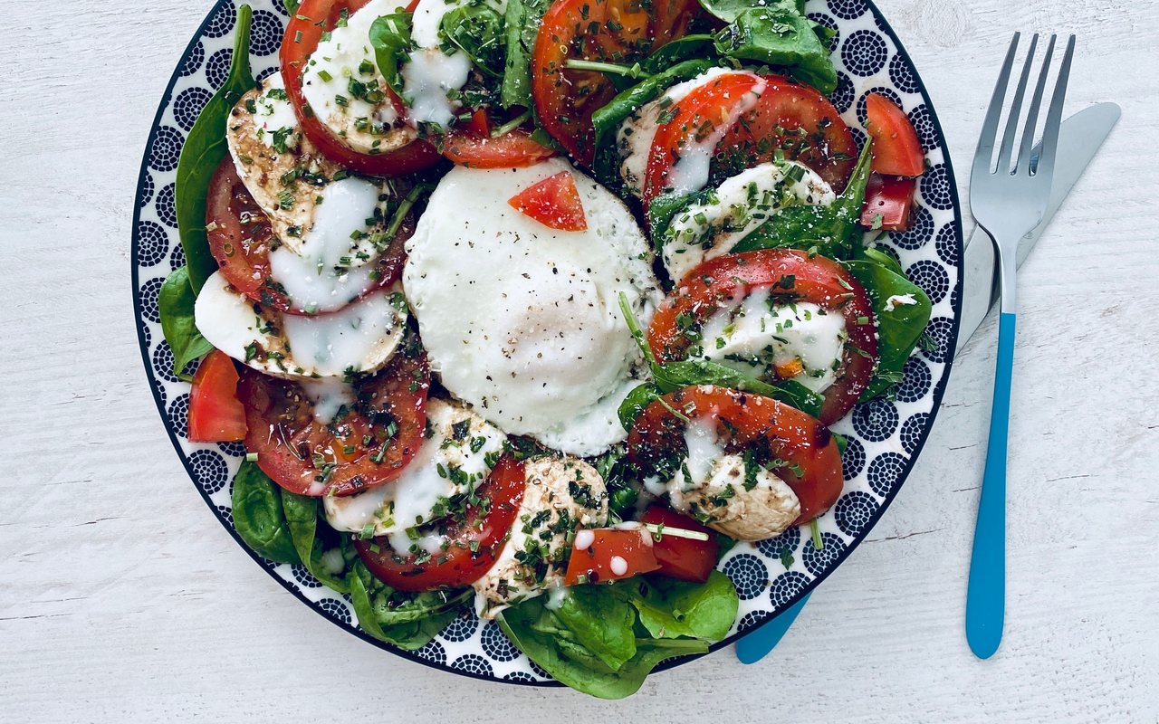 Sliced tomatoes and fresh mozzarella arranged with arugula on a serving plate