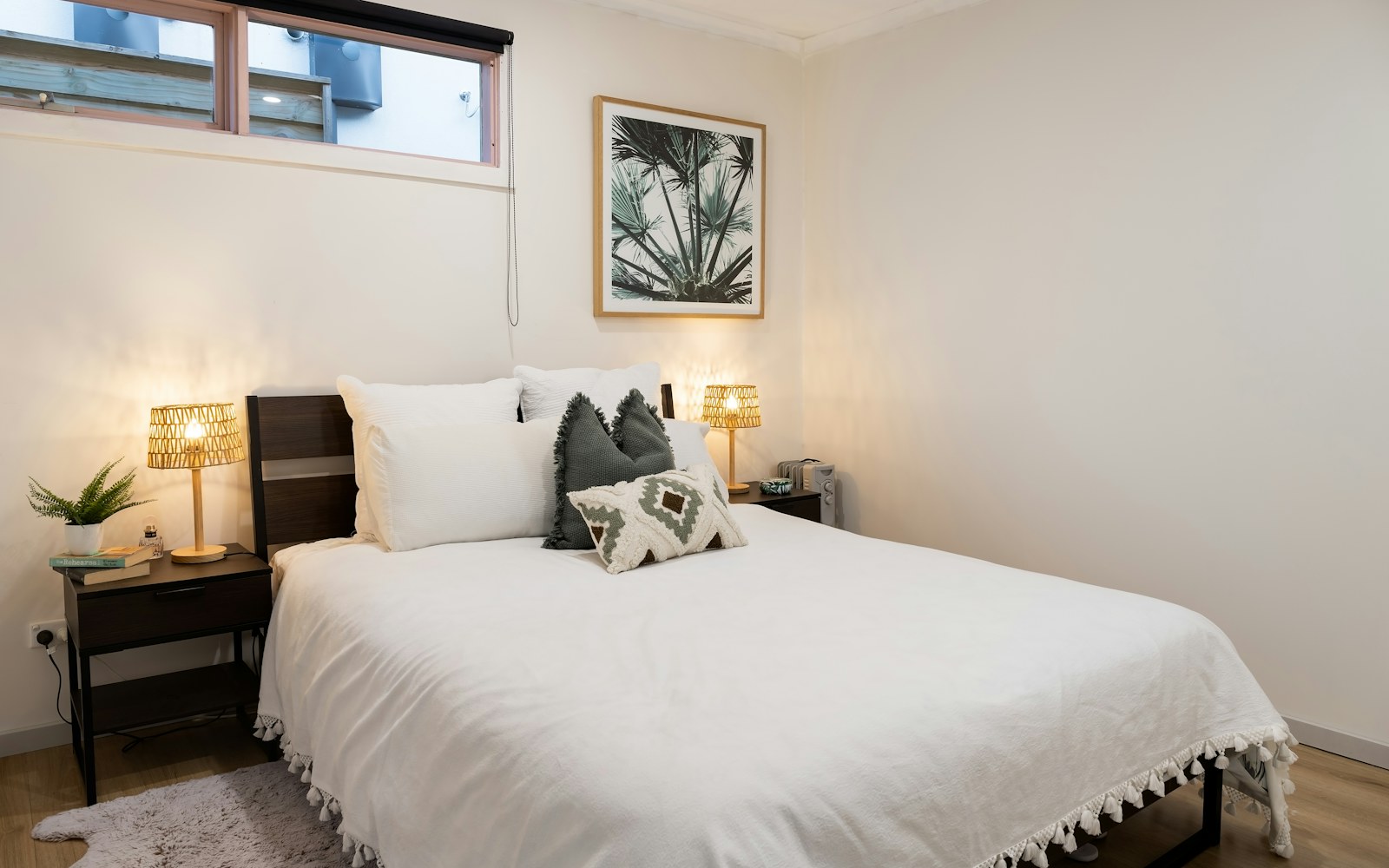 Neatly made bed with pillows and warm bedside lamps