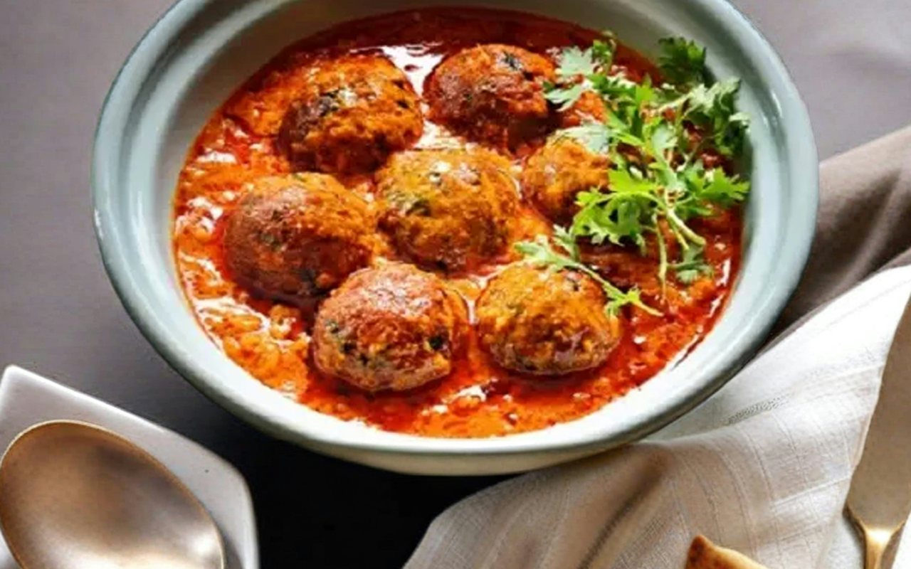 Meatballs in red tomato sauce topped with parsley and served with flatbread.