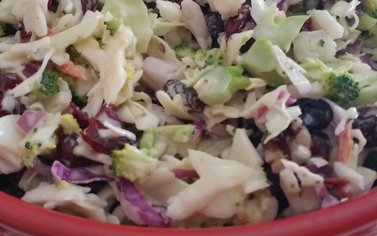 Creamy cabbage and broccoli coleslaw with carrot, raisins, and dried cranberries