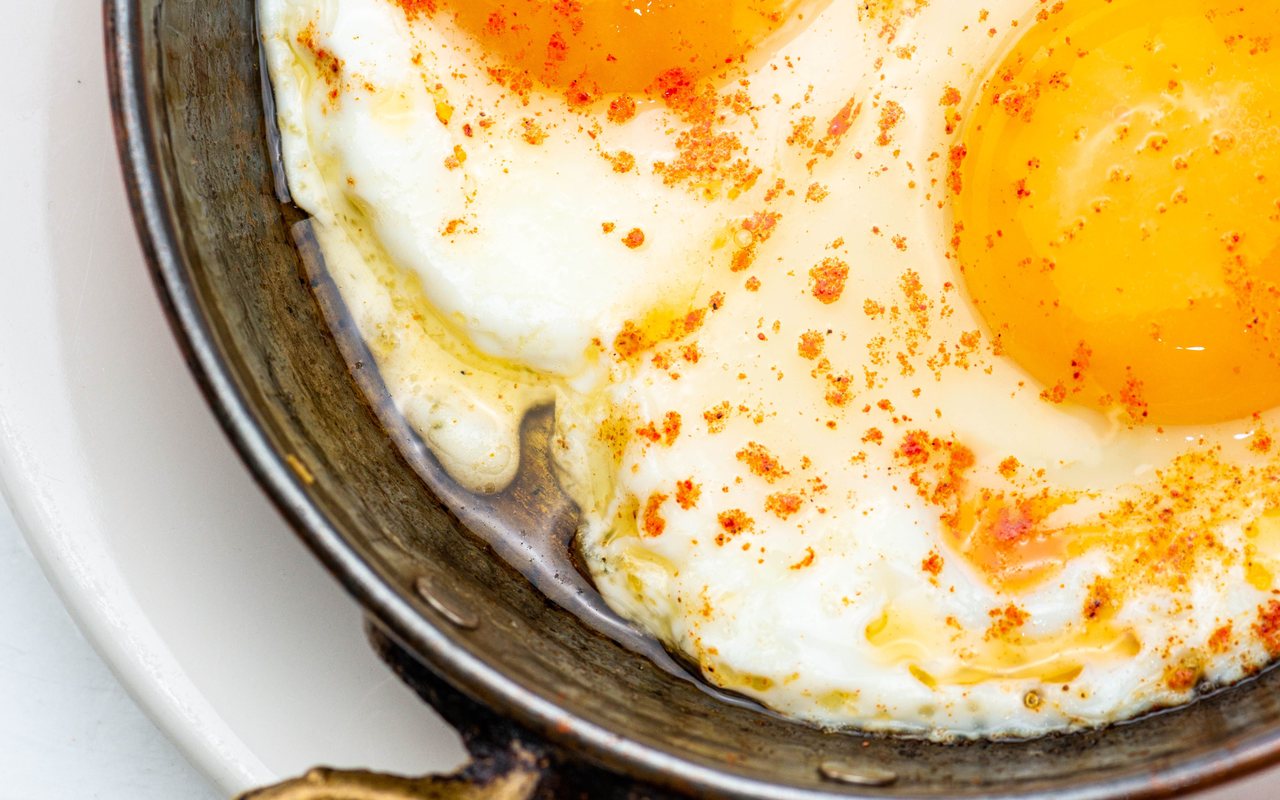 Skillet eggs with toasted sesame, nigella seeds, hot sauce, and herbs