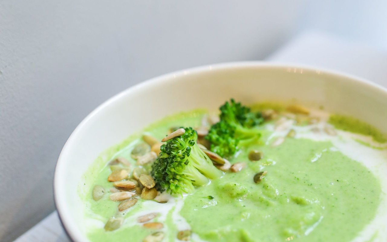 Smooth green broccoli soup in a white bowl