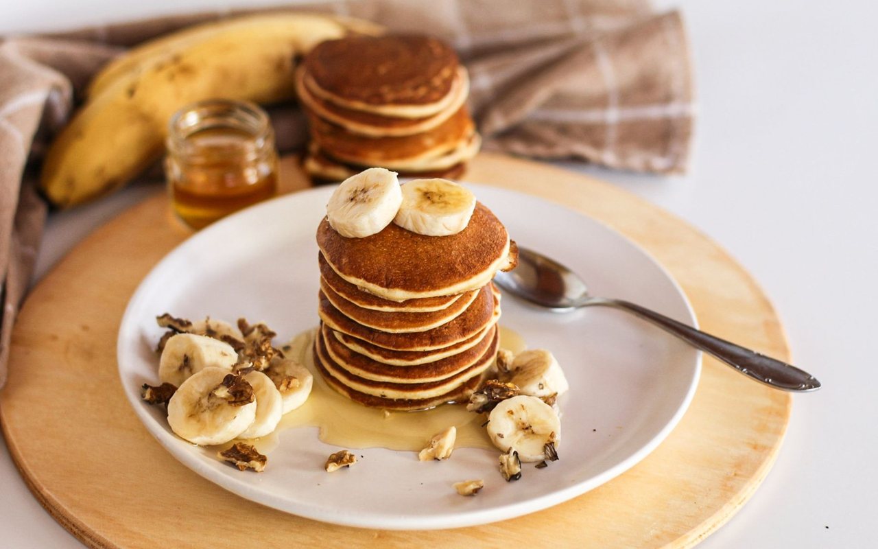 Small golden banana pancakes stacked on a plate
