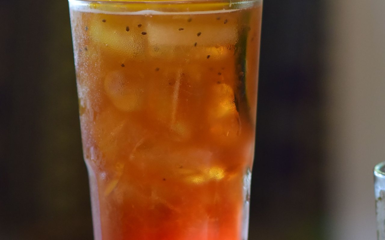 Peach iced tea with peach slices and ice in a clear glass