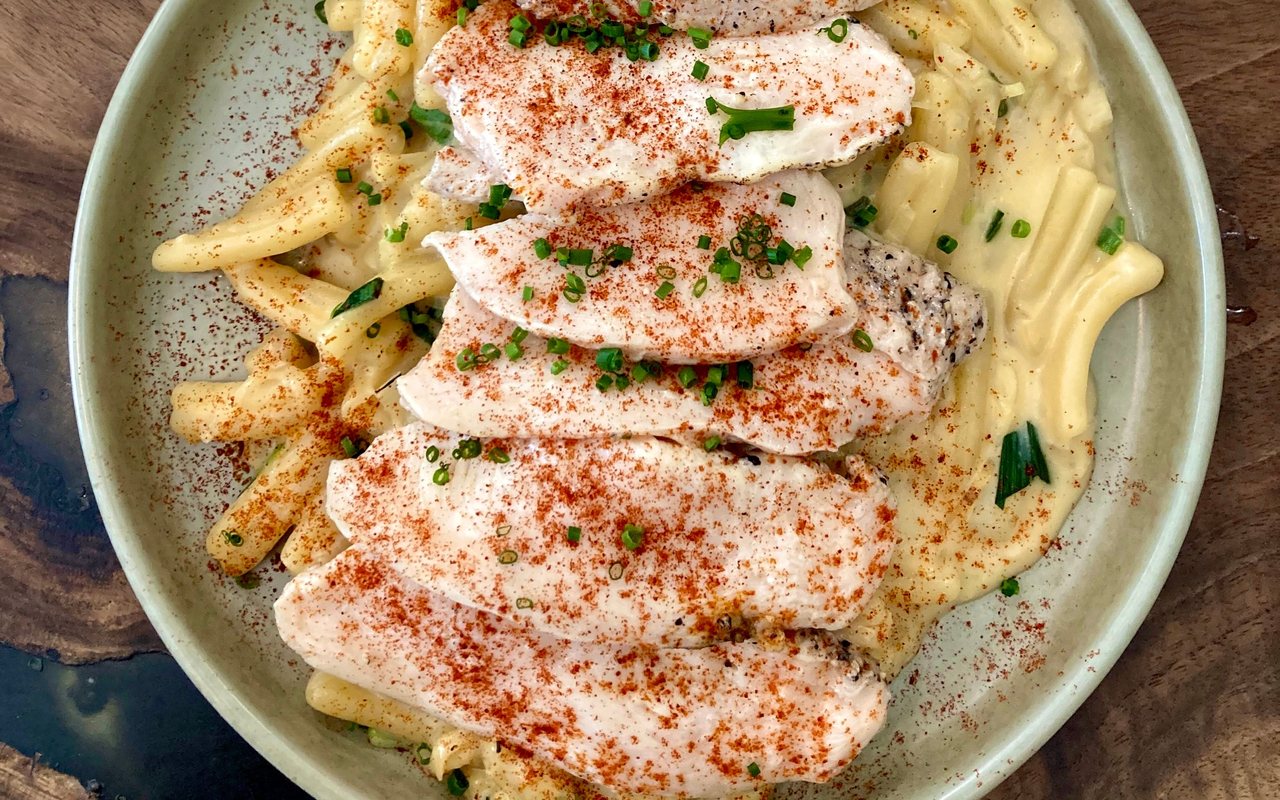 Sliced chicken breast over creamy short pasta with chives and paprika