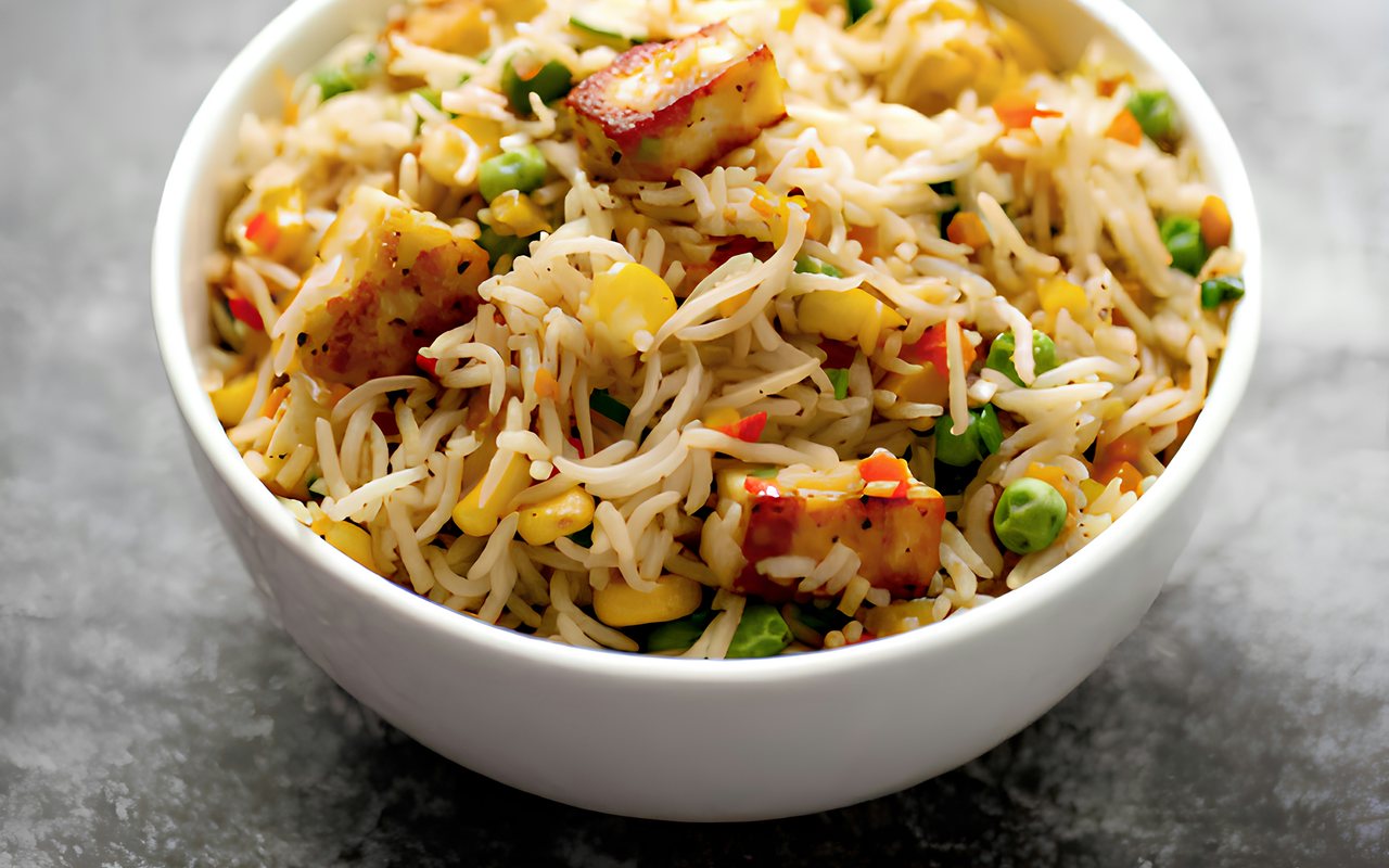Fried rice with browned tofu, carrots, peas, scallions, and mixed vegetables in a bowl.