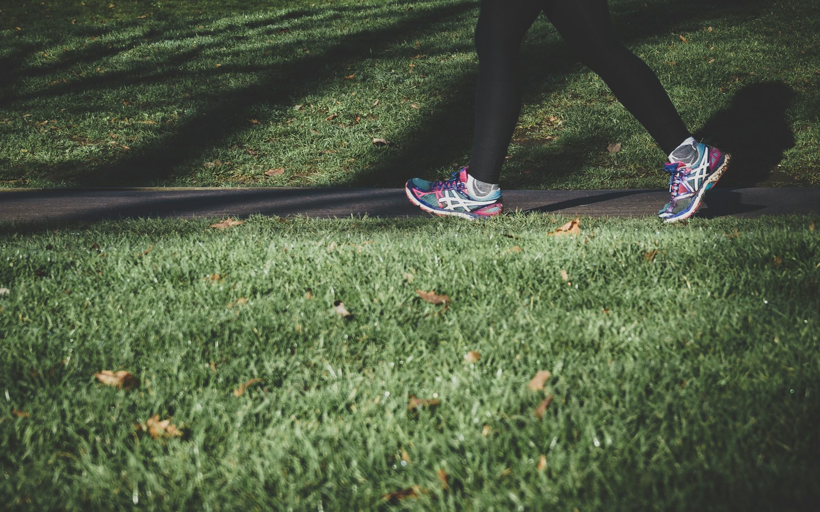 Close-up of a person walking beside a grass-lined path