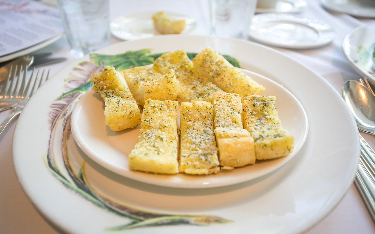 Baguette quarters topped with melted cheese, garlic, parsley, rosemary, and thyme