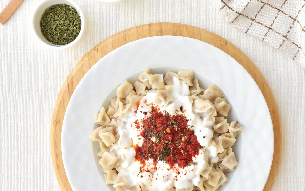 Small Turkish mantı dumplings topped with garlic yogurt and red pepper sauce
