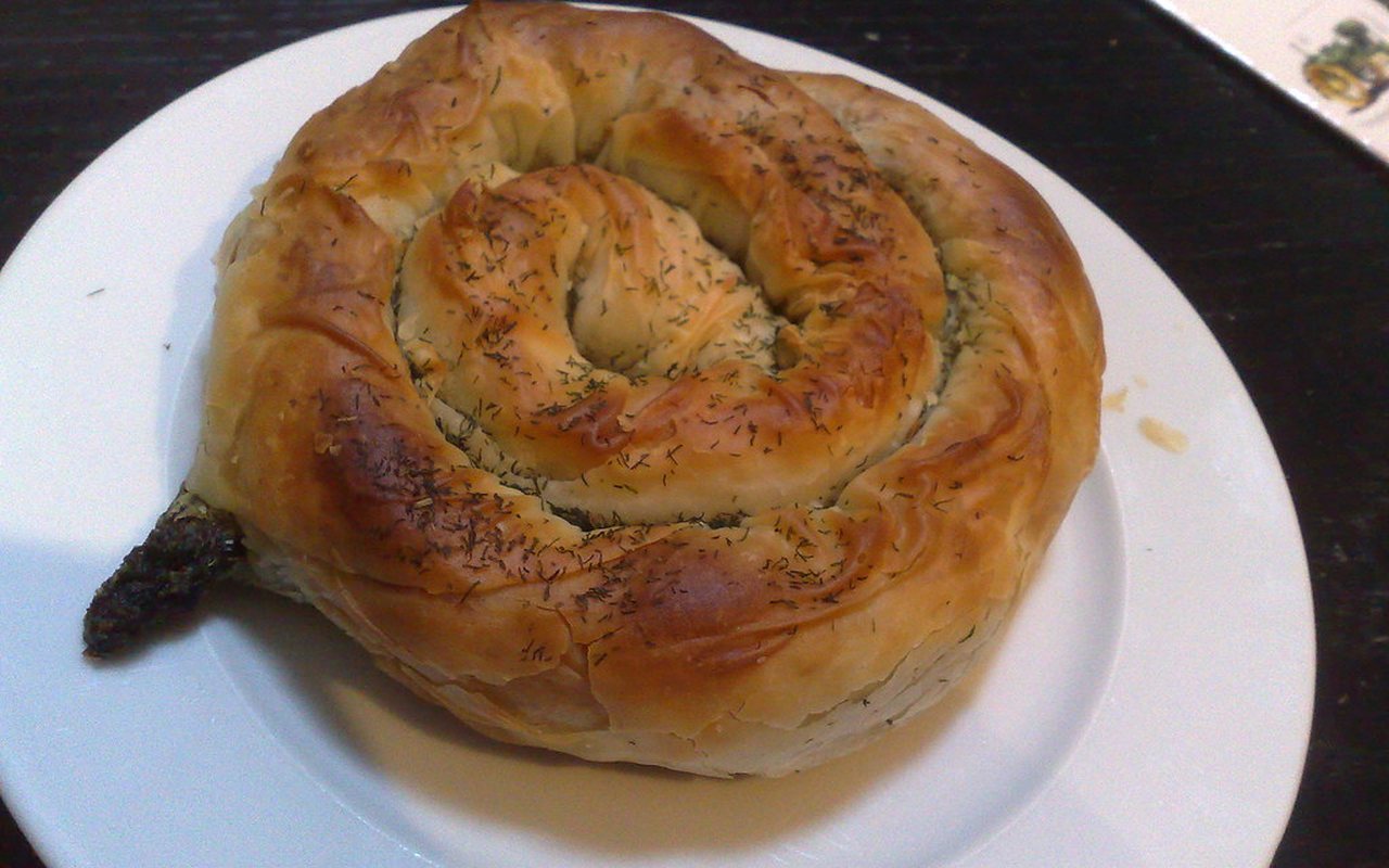 Spiral spinach börek with a golden crust in a round baking dish