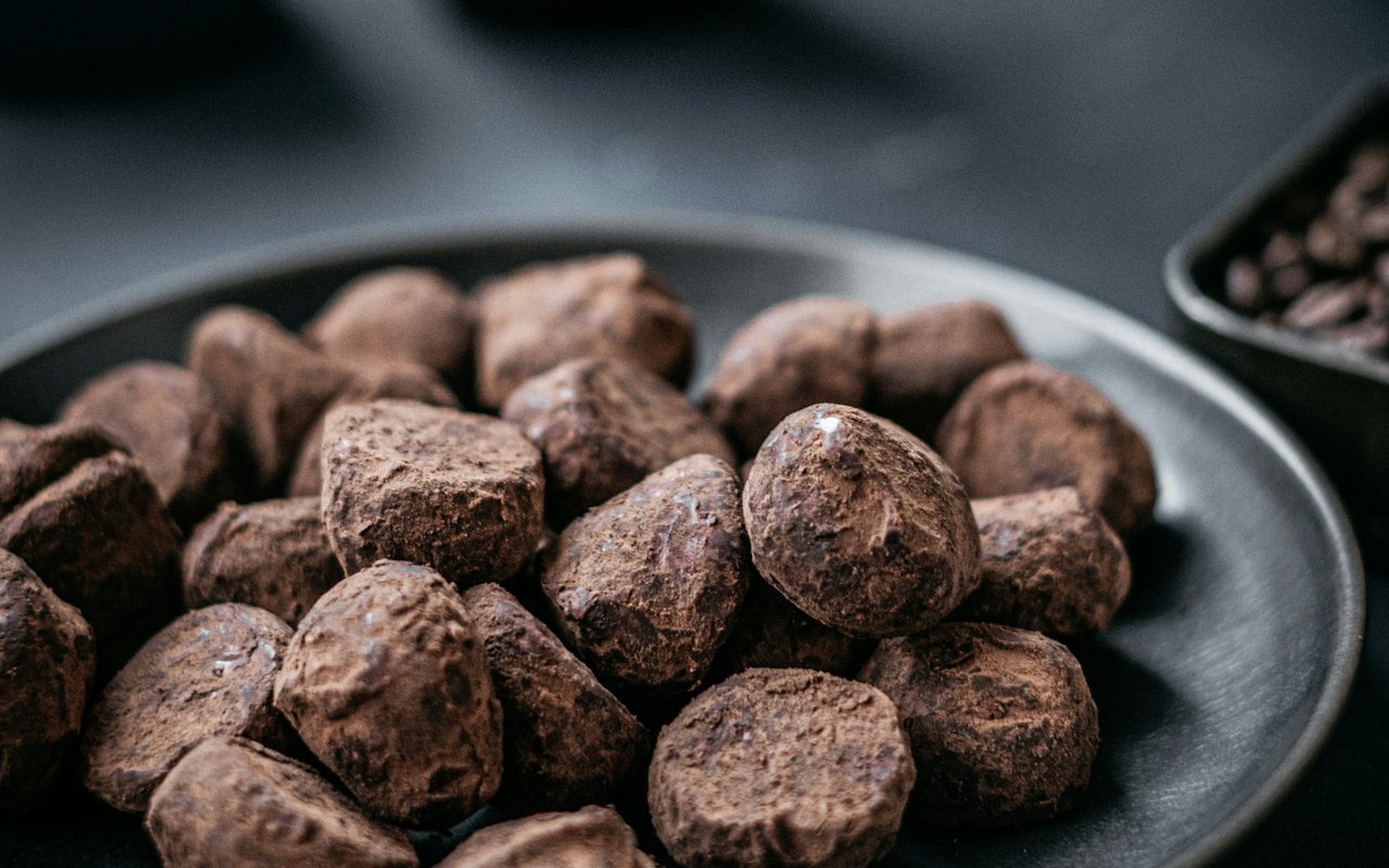 Cocoa-dusted chocolate truffles piled on a black plate.