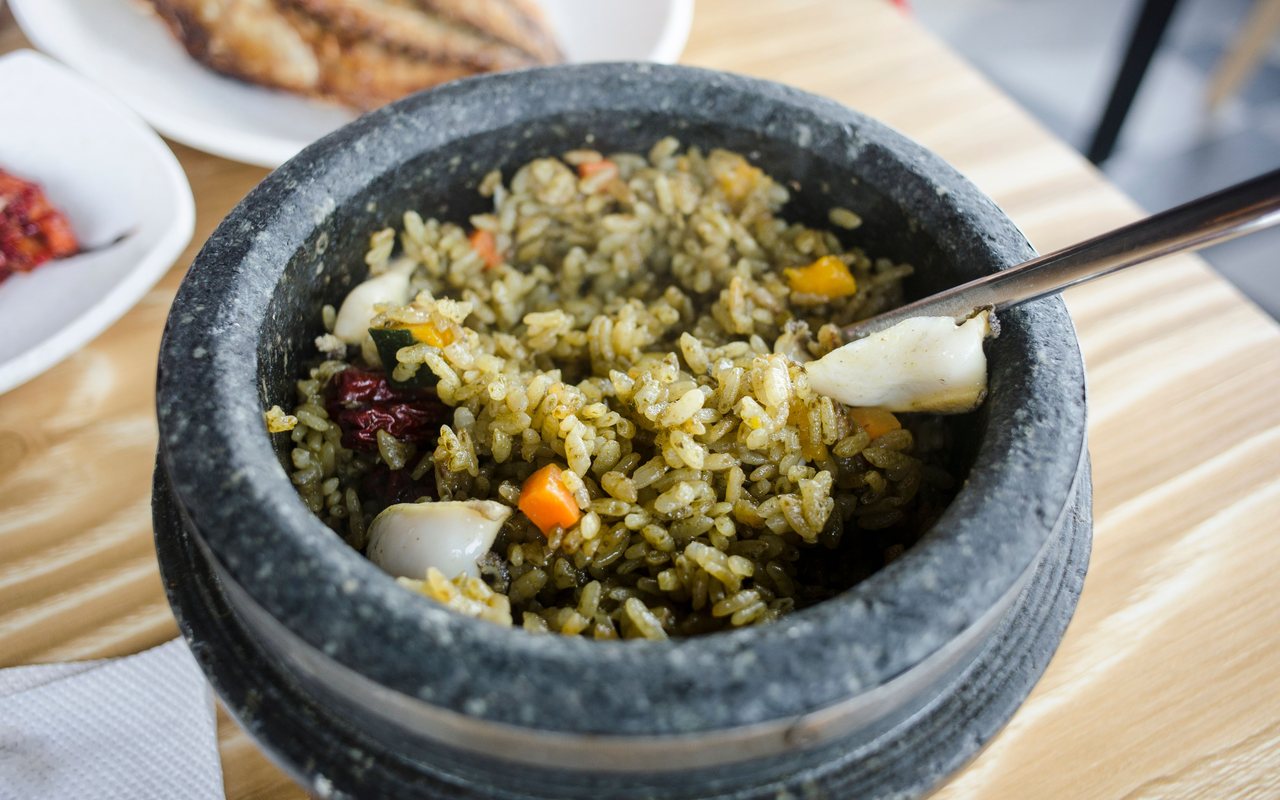 Green-seasoned rice with diced orange and yellow vegetables in a dark stone bowl