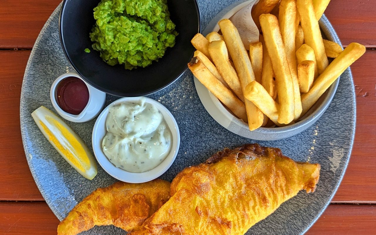 Golden battered fish and thick-cut chips with tartar sauce and mashed peas