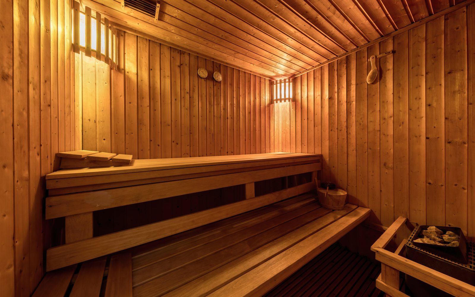 Empty wooden sauna with tiered benches and warm interior lighting.