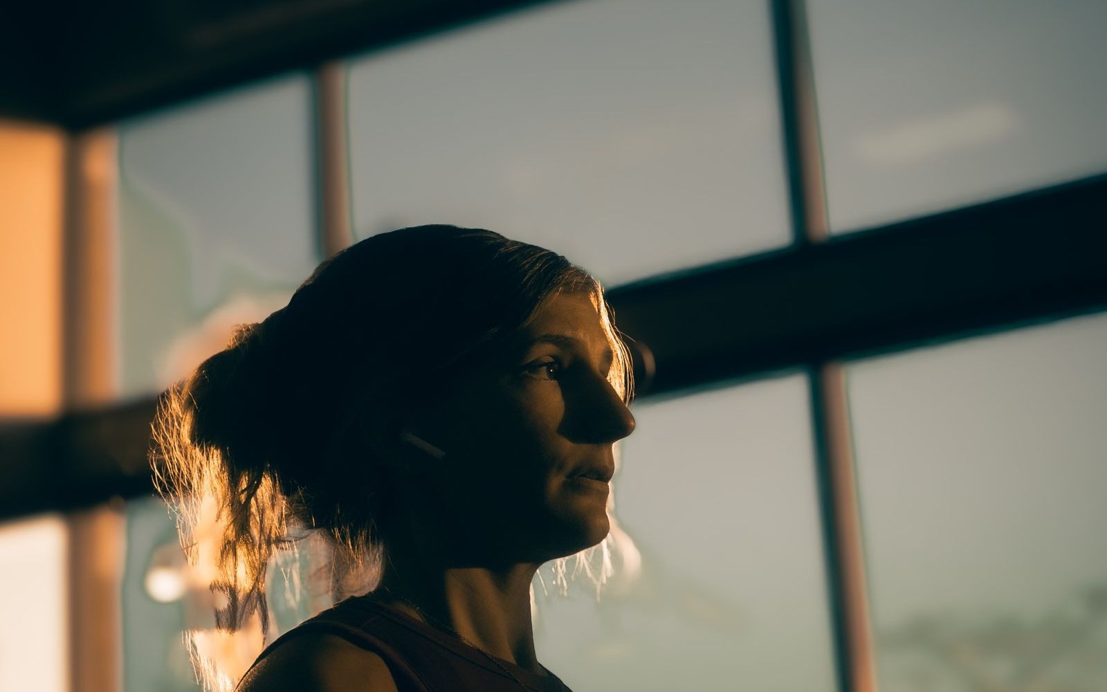 Woman in workout clothes standing in a sunset-lit studio.